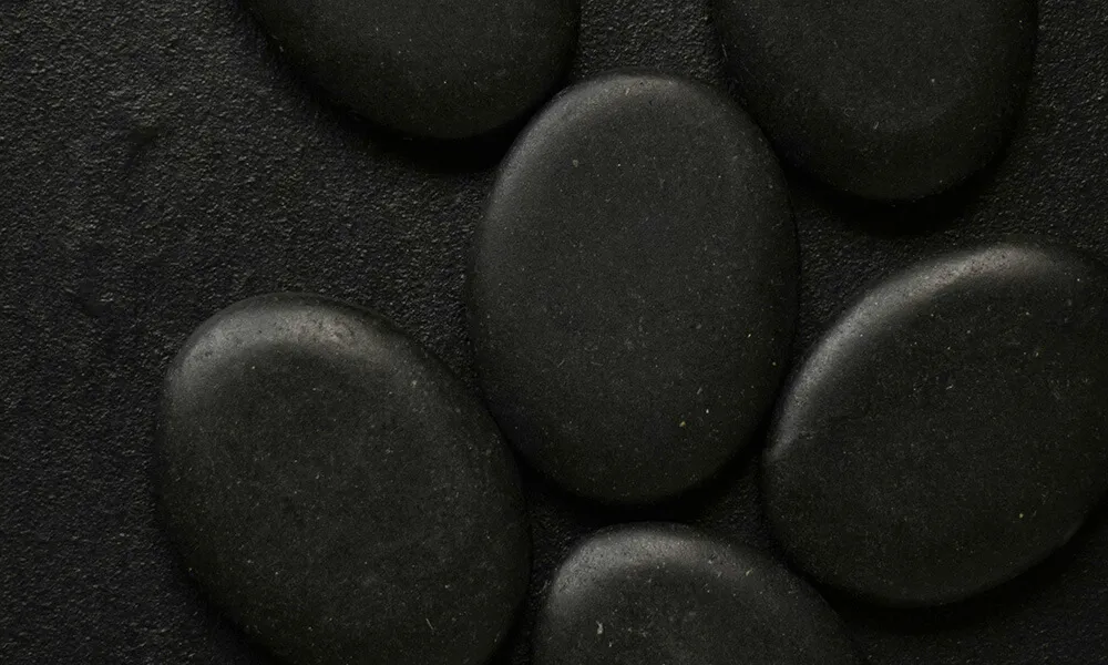 What Are the Contraindications for Hot Stone Massage? | A Servants Hands Massages Stones on black table