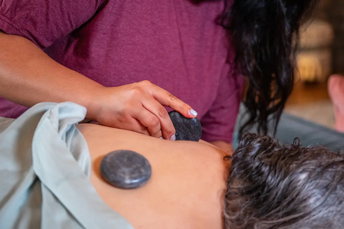 A massage therapist using hot stones during a massage