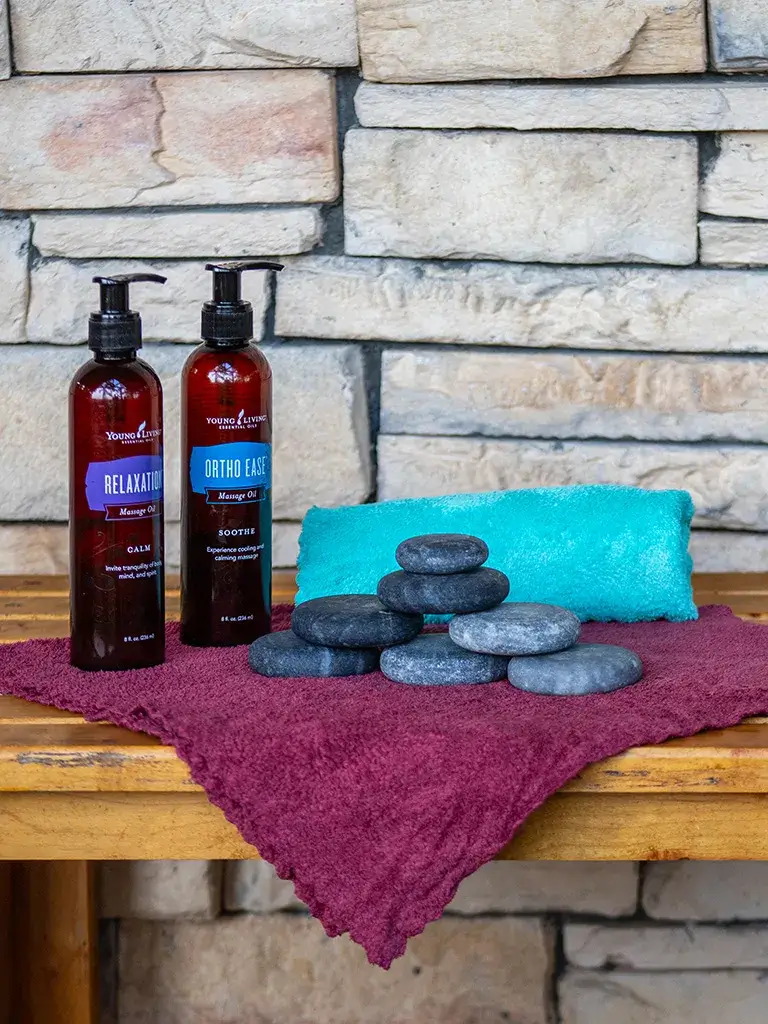 massage-therapy-products Massage oils, a hot towel, and a stack of hot stones